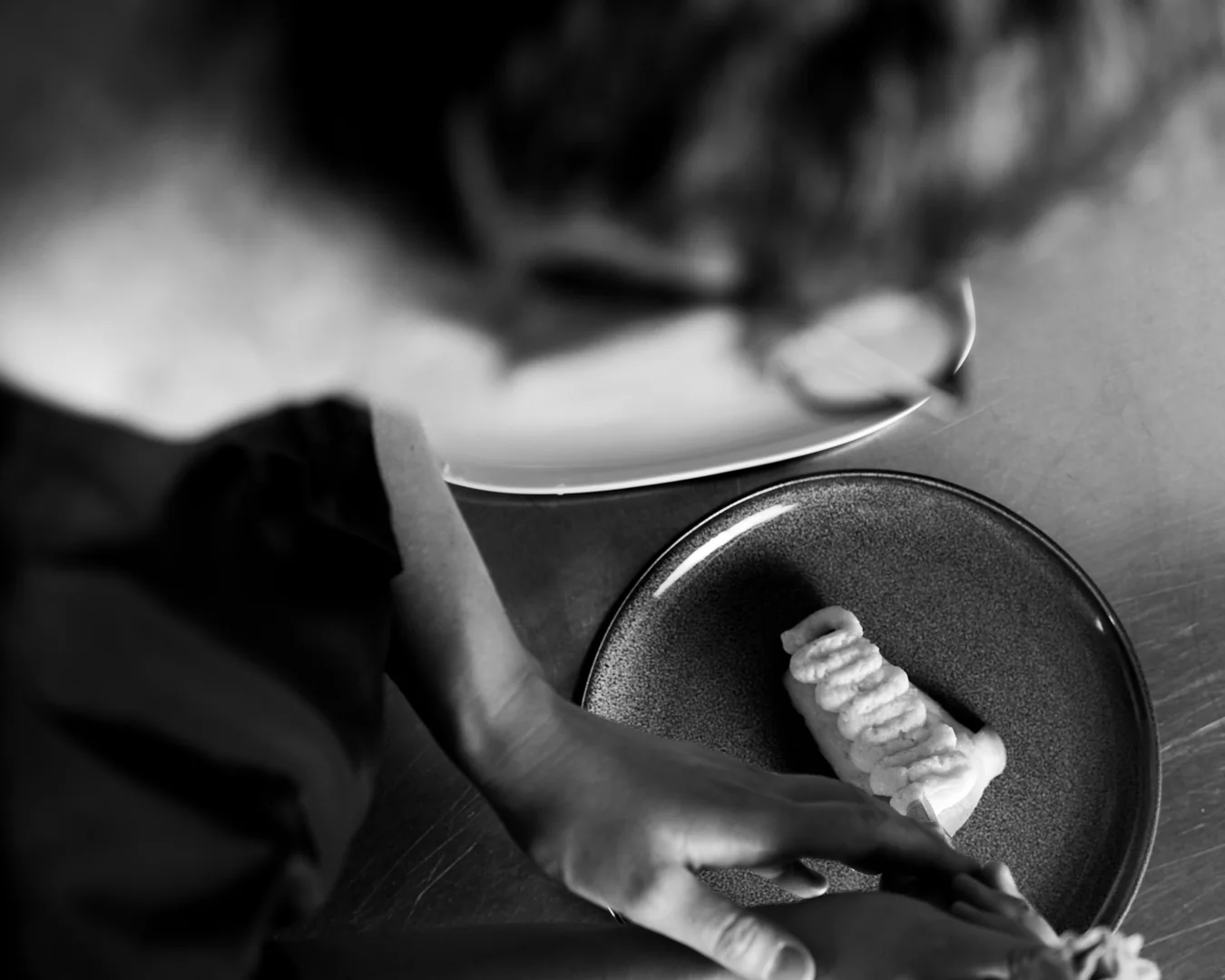 Pilar Toledo rifinisce un piatto, in bianco e nero