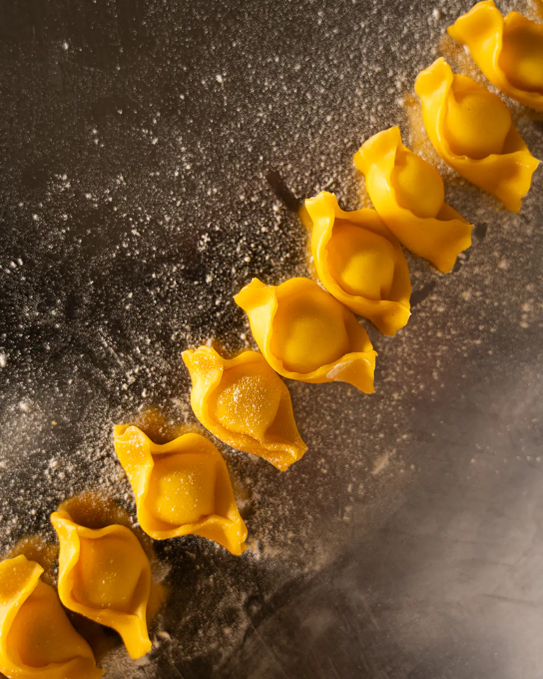 Tortelli di pasta fresca appena chiusi sul banco infarinato